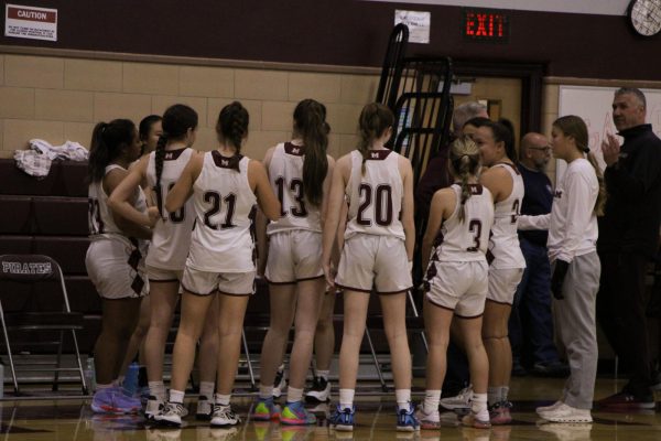 Girls varsity basketball team converses during a timeout.